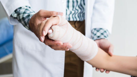 A doctor examining hand of a patient with hand fracture.