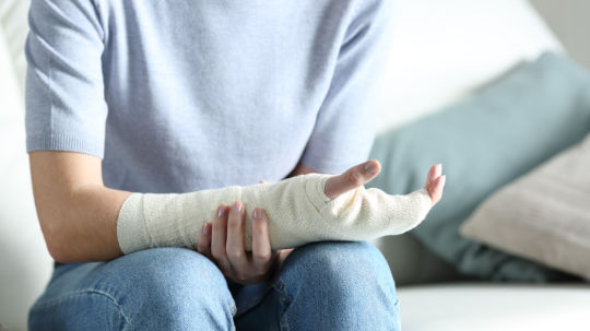 A woman with bandaged hand due to wrist fracture.