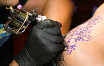 a specialist is doing a tattoo on womans back